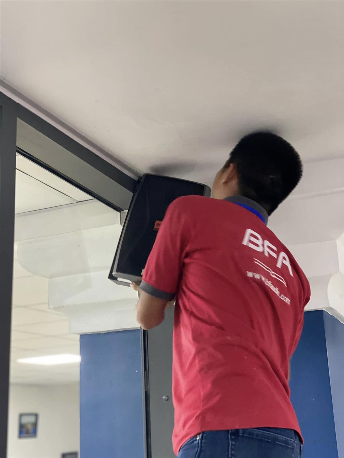 Kỹ thuật viên BFA lắp loa treo tường tại công trình phòng họp